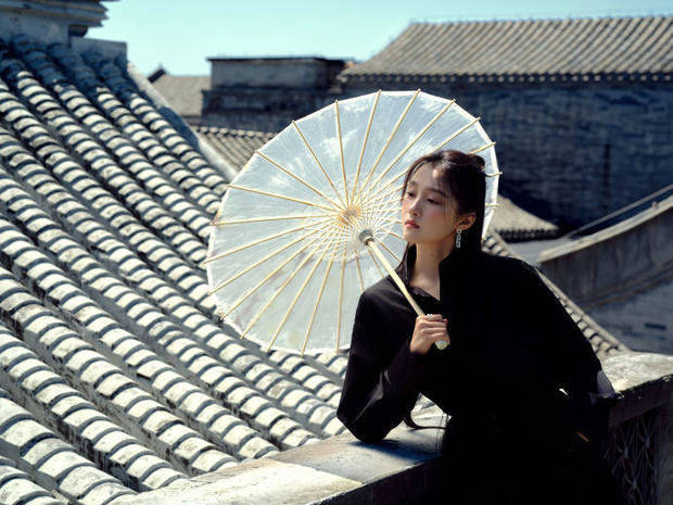 关晓彤凭栏持伞，眼神悠远。